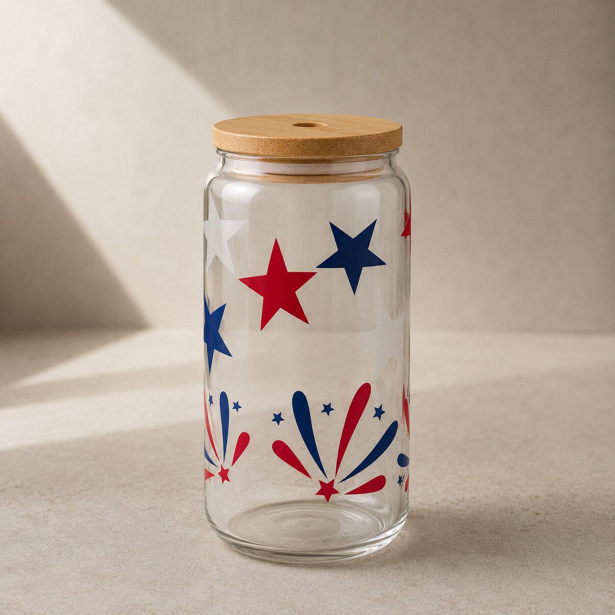 Clear glass jar with wooden lid featuring red and blue star and firework design on a beige background