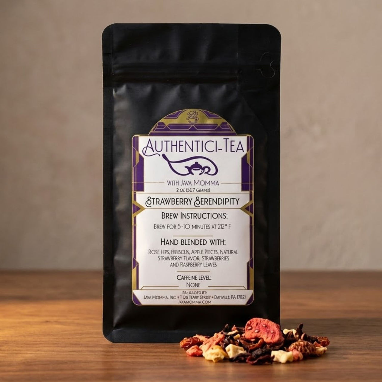 Authentic-Tea Strawberry Serendipity herbal tea in a black pouch with loose strawberry fruit blend spilled on a wooden surface against a warm neutral background.