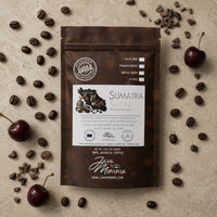 Thumbnail for Overhead flatlay of Java Momma Sumatra Satin Dark Roast coffee bag with whole coffee beans, dark cherries, and cacao nibs