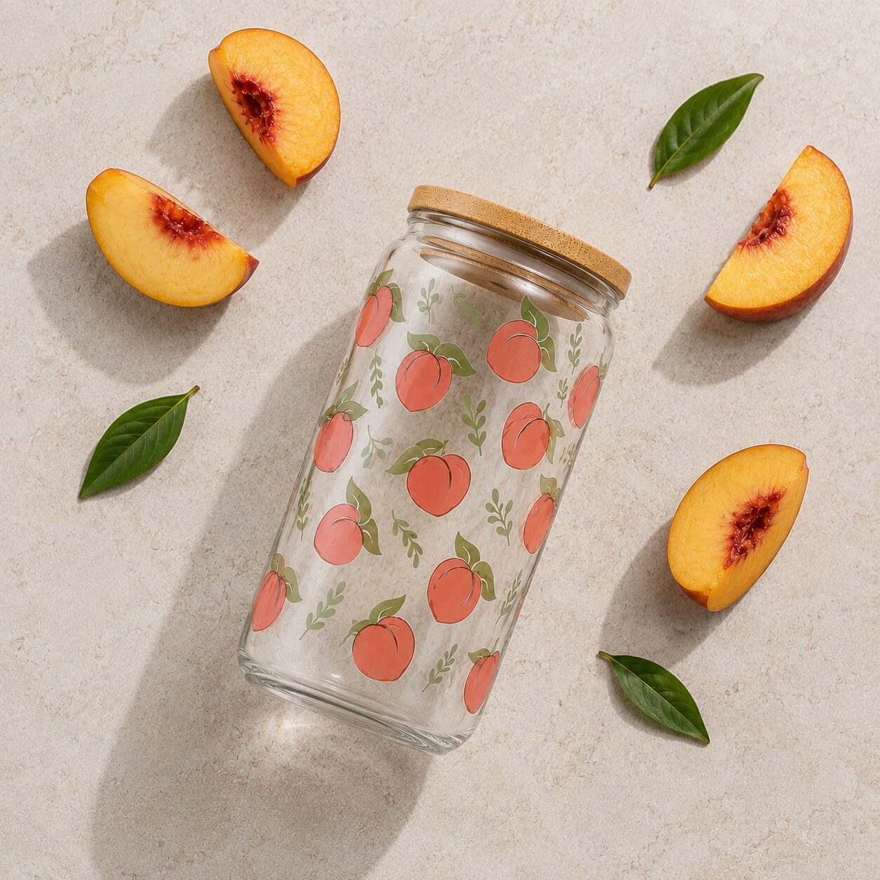Glass tumbler with peach pattern and wooden lid surrounded by sliced peaches and leaves on a light background