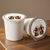 Thumbnail for Three Beans Butter Beer single serve coffee pods on a wooden surface with label artwork visible and warm neutral background.