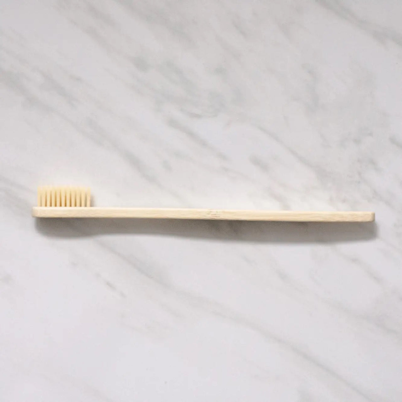 The Bamboo Toothbrush – Eco-Friendly, Biodegradable Handle & Medium Bristles rests flat on a white marble surface.