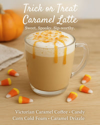 Thumbnail for A glass mug of Victorian Caramel Flavored Coffee, Keurig compatible, sits on a wooden table with foam and caramel drizzle, surrounded by candy corn and a small pumpkin. The text describes this drink as a delicious Caramel Latte.