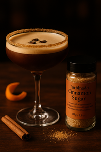 Thumbnail for A coupe glass rimmed with Turbinado Cinnamon Sugar 🧁 – Sweet, Spicy, and Everything Nice – sits beside a jar of the sugar, Korintje cinnamon sticks, a sugar crescent, and coffee beans on a dark wooden surface.