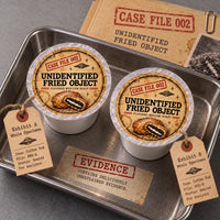 Thumbnail for Unidentified Fried Object Coffee | Momma's Picks coffee pods with case file labels and evidence tags on a tray.