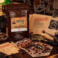 Thumbnail for Unidentified Fried Object Coffee | Momma's Picks bag next to fried cookie and evidence papers in a rustic setup.
