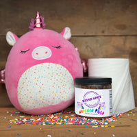 Thumbnail for Pink plush unicorn toy with a jar of 'Blind Spot' unicorn poop on a wooden surface.