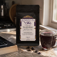 Thumbnail for Java Momma Wild Blueberry Black tea package with label and a glass of brewed tea on a kitchen counter.
