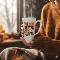 Thumbnail for A person in a brown sweater holds the limited edition 17 oz Witch Better Have My Coffee Mug, sitting by a window with autumn leaves and a plaid blanket nearby.